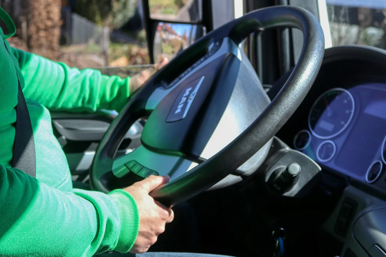 A driver&rsquo;s hands on the wheel of a truck, the dashboard lit.