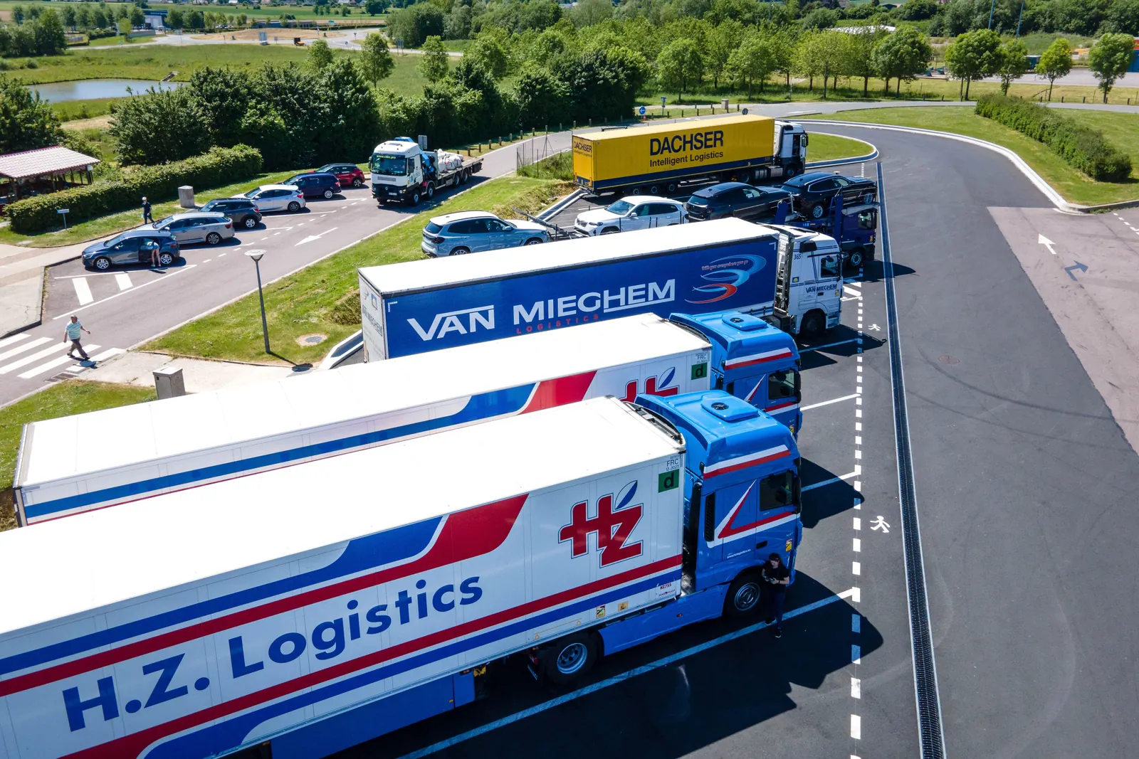 Trucks parked at a motorway services, seen from above, with a driver walking between them.